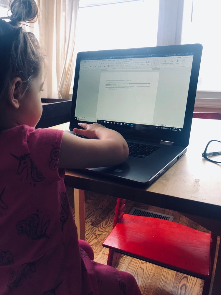 Child working on a laptop at home during remote work or study.