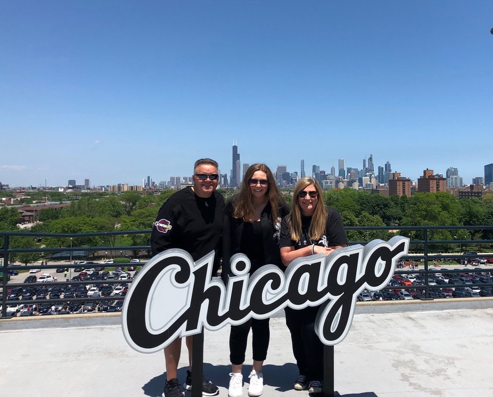 Group of three people standing with Chicago skyline in background.
