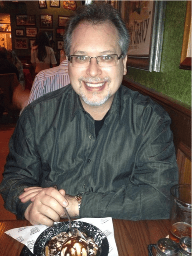 Smiling man in glasses enjoying dessert at a restaurant.