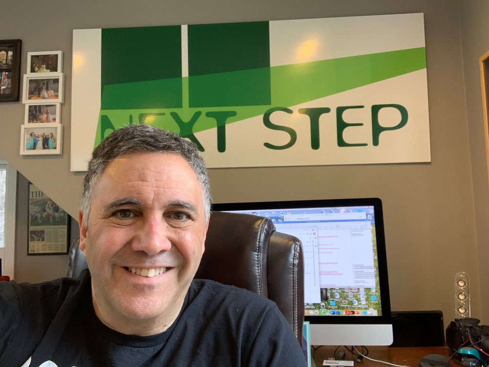 Smiling man working from home with iD Additives logo in background.